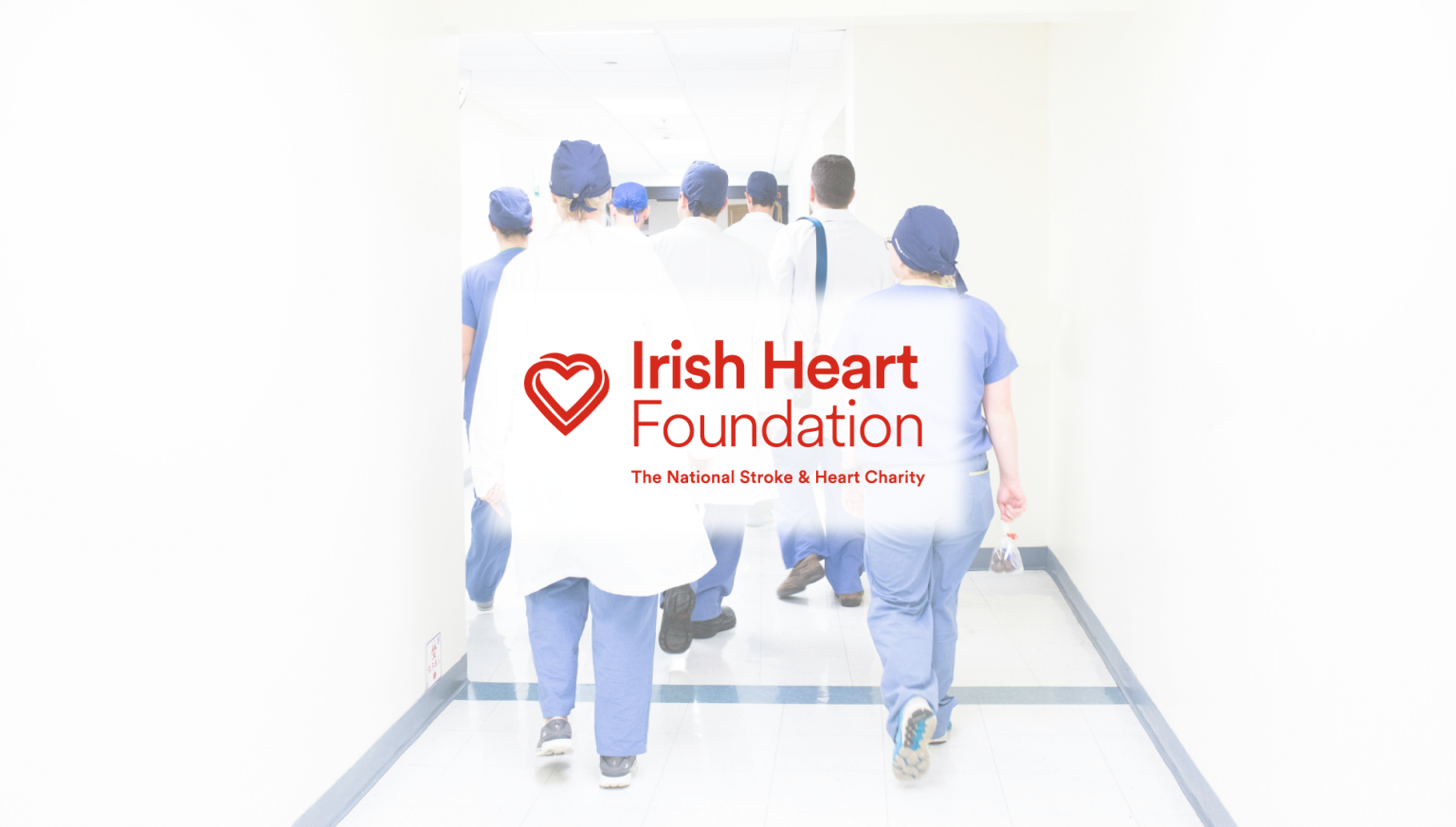 Group of healthcare professionals walking down a hospital corridor, with the Irish Heart Foundation logo and tagline 'The National Stroke & Heart Charity' prominently displayed in the foreground. Represents heart health awareness and medical support.